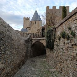 Carrer empedrat de Carcassone amb unes torres del castell al fons.