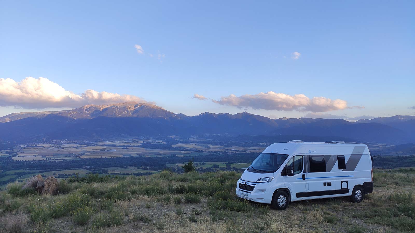 Foto de la Camper aparcada al capvespre en un altiplà amb una plana i unes muntanyes al fons.