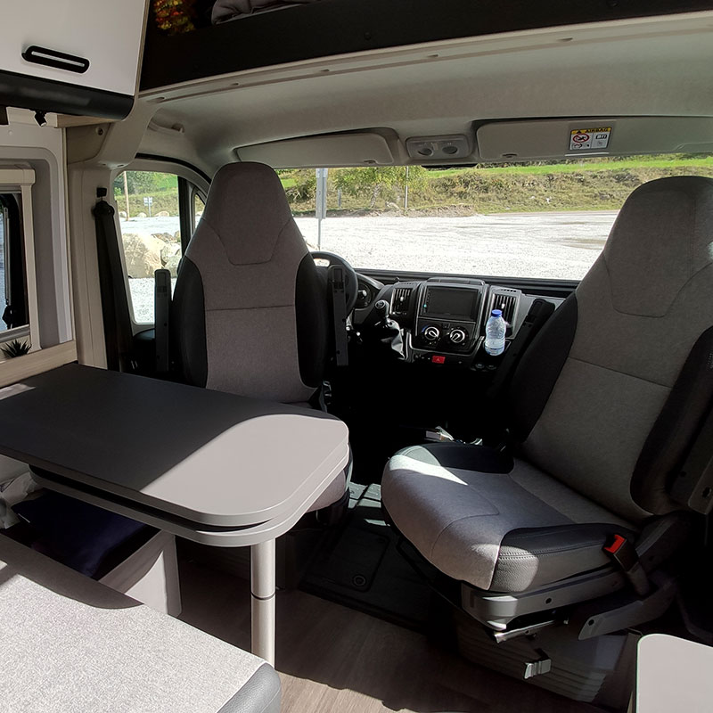 Foto interior de La Camper amb una taula i els seients del conductor i el copilot girats.